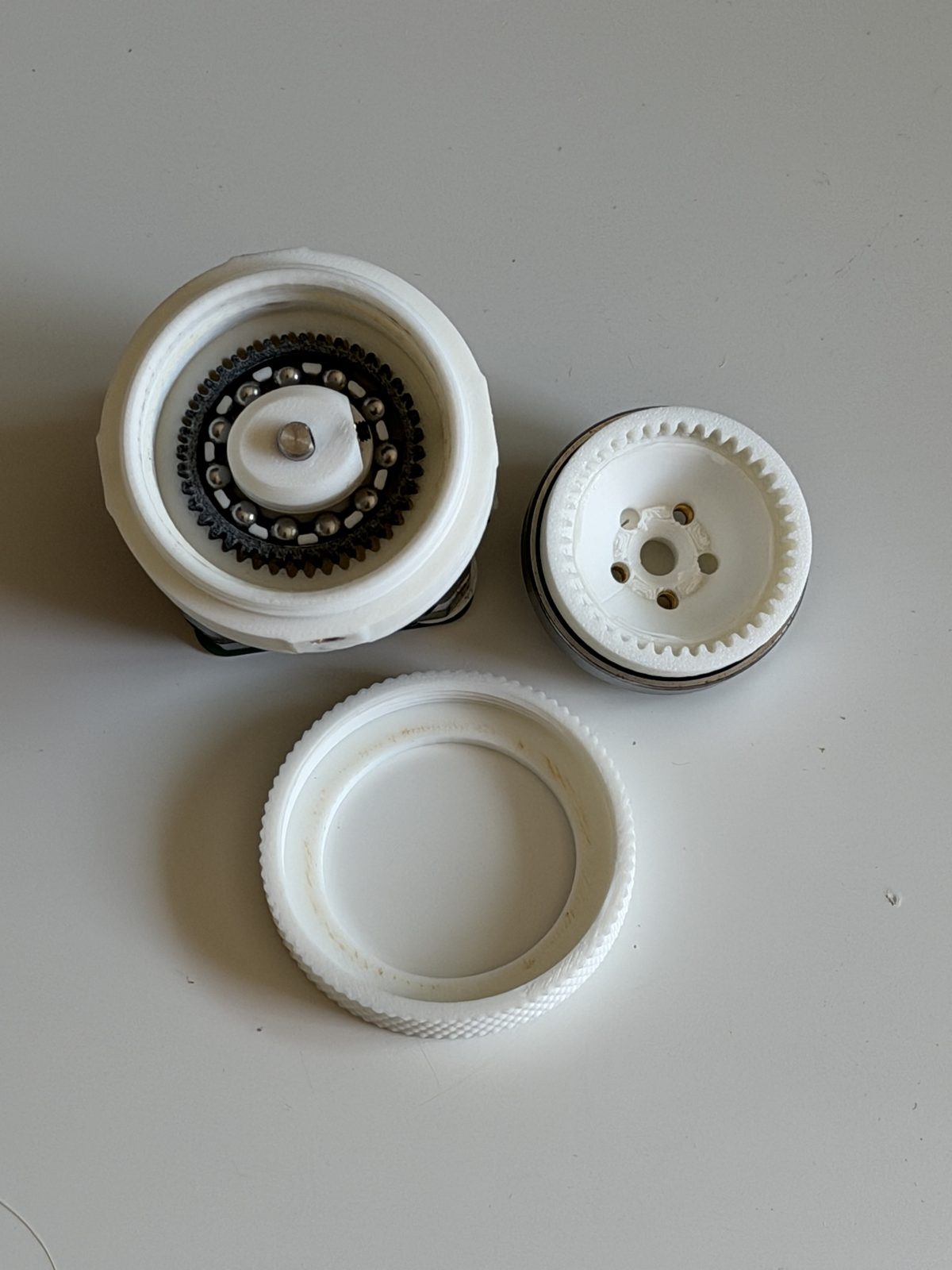 The three main subassemblies of the HD20 laid out from above: the motor-mounted body with the ball-cage wave generator, the toothed output spline, and the knurled outer ring.