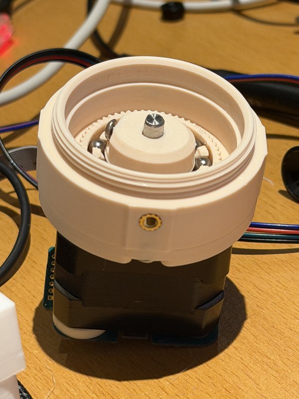 Looking into the open drive: the cream circular spline, the flexspline teeth, the steel balls in the printed cage, and the wave generator clamped to the motor shaft.